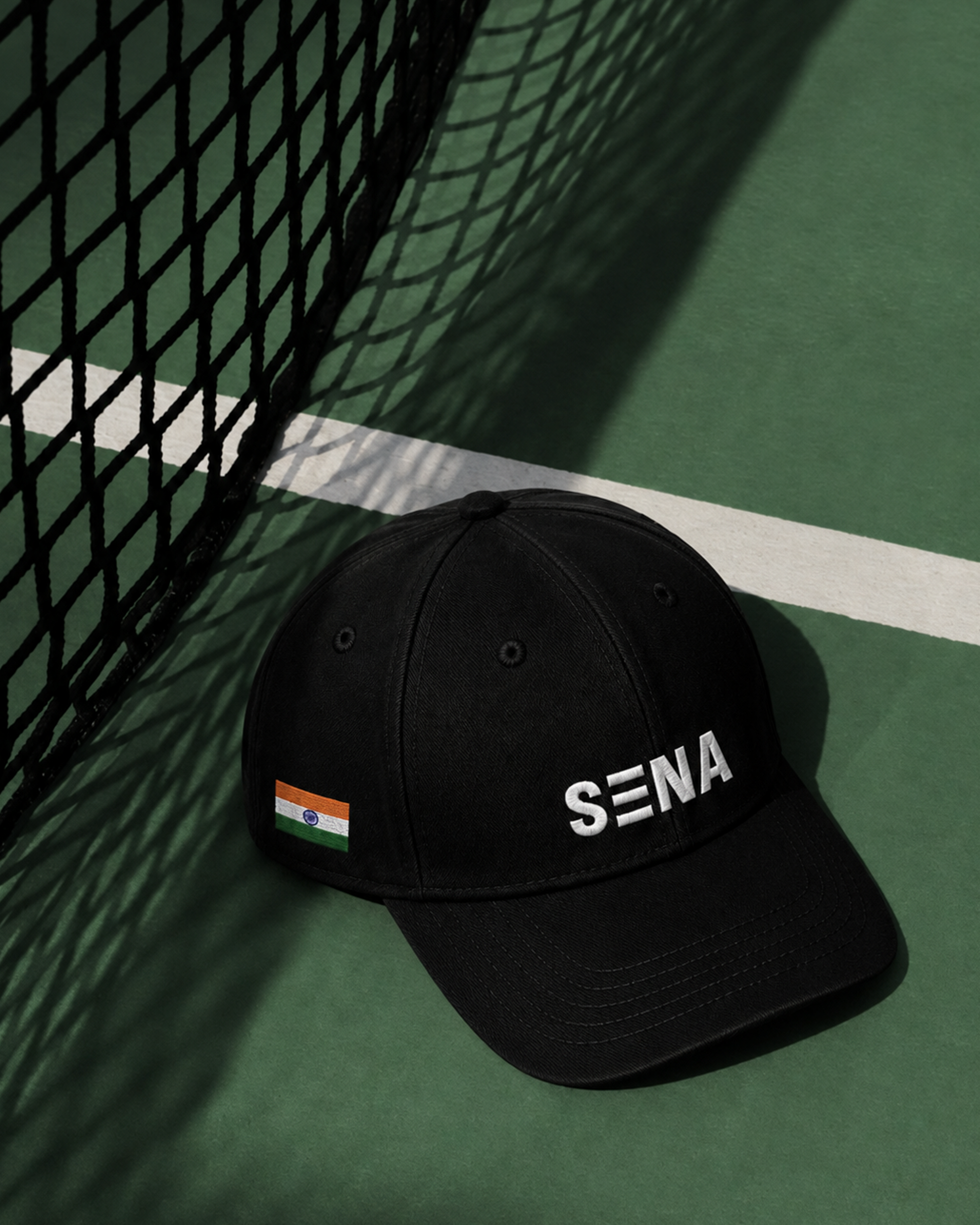Black cap with 'SENA' logo on a tennis court