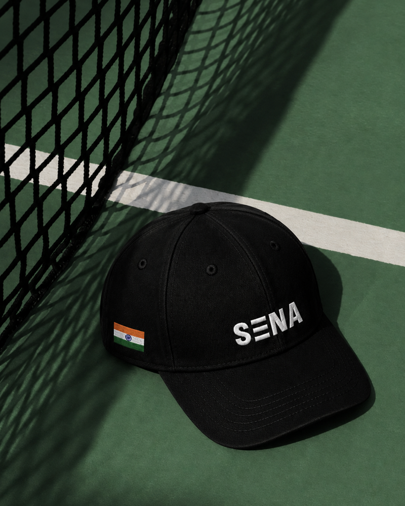 Black cap with 'SENA' logo on a tennis court